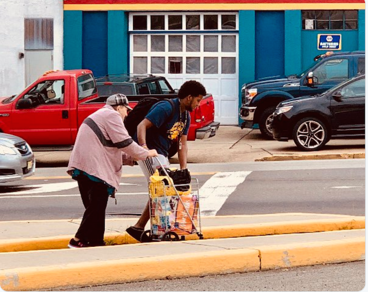 Sophomore Kidus Mengistu is seen helping an elderly woman cross the street outside of the high school.