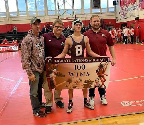 Michael Rodriguez shows off his accomplishment of 100 wins, standing proud with his coaches. 
