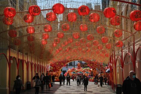 Lanterns hang in the streets, as a celebration of Lunar New Year, while those below practice social-distancing.